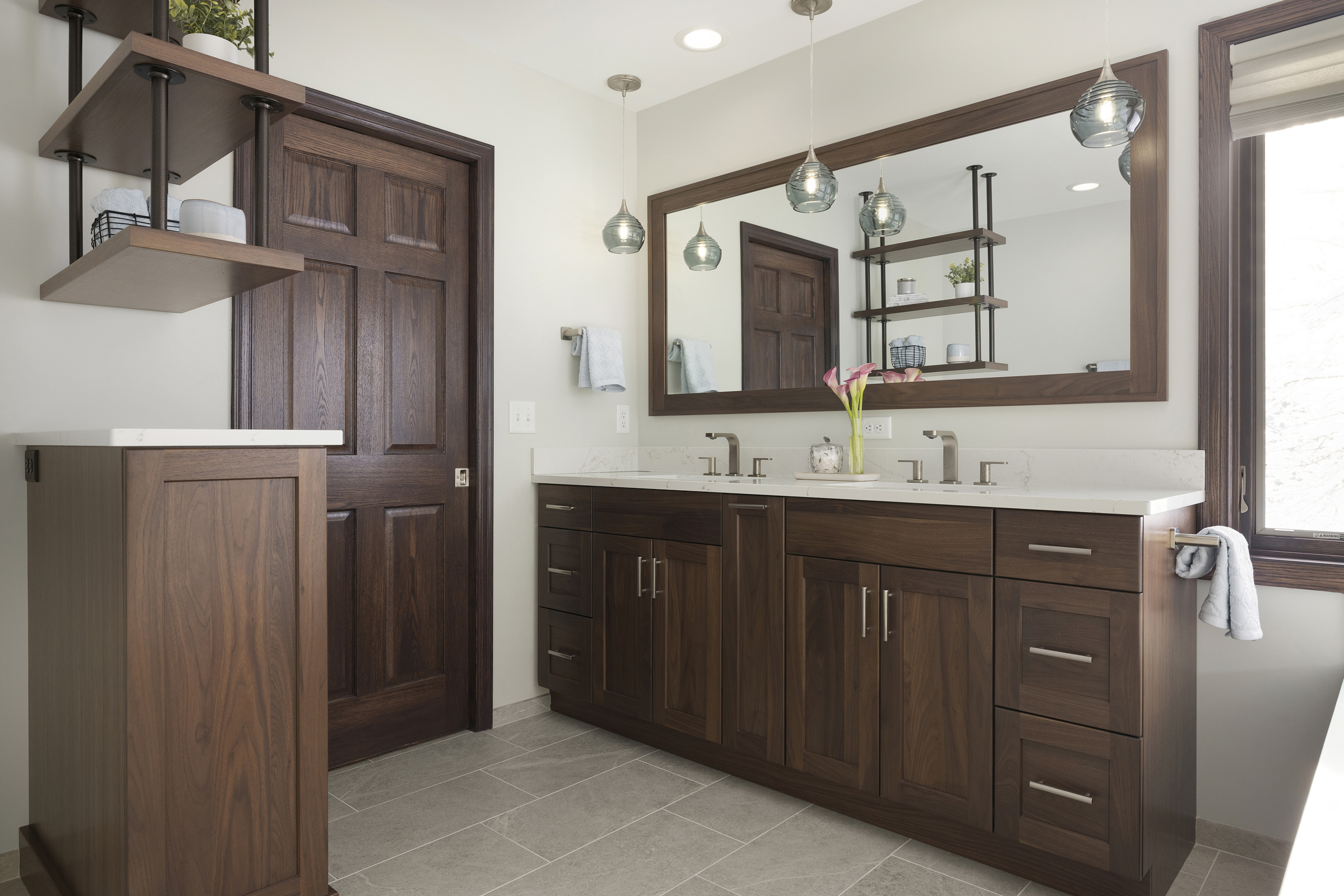 Primary bathroom remodel with dark wood cabinets and trim and hanging shelves to separate toilet area