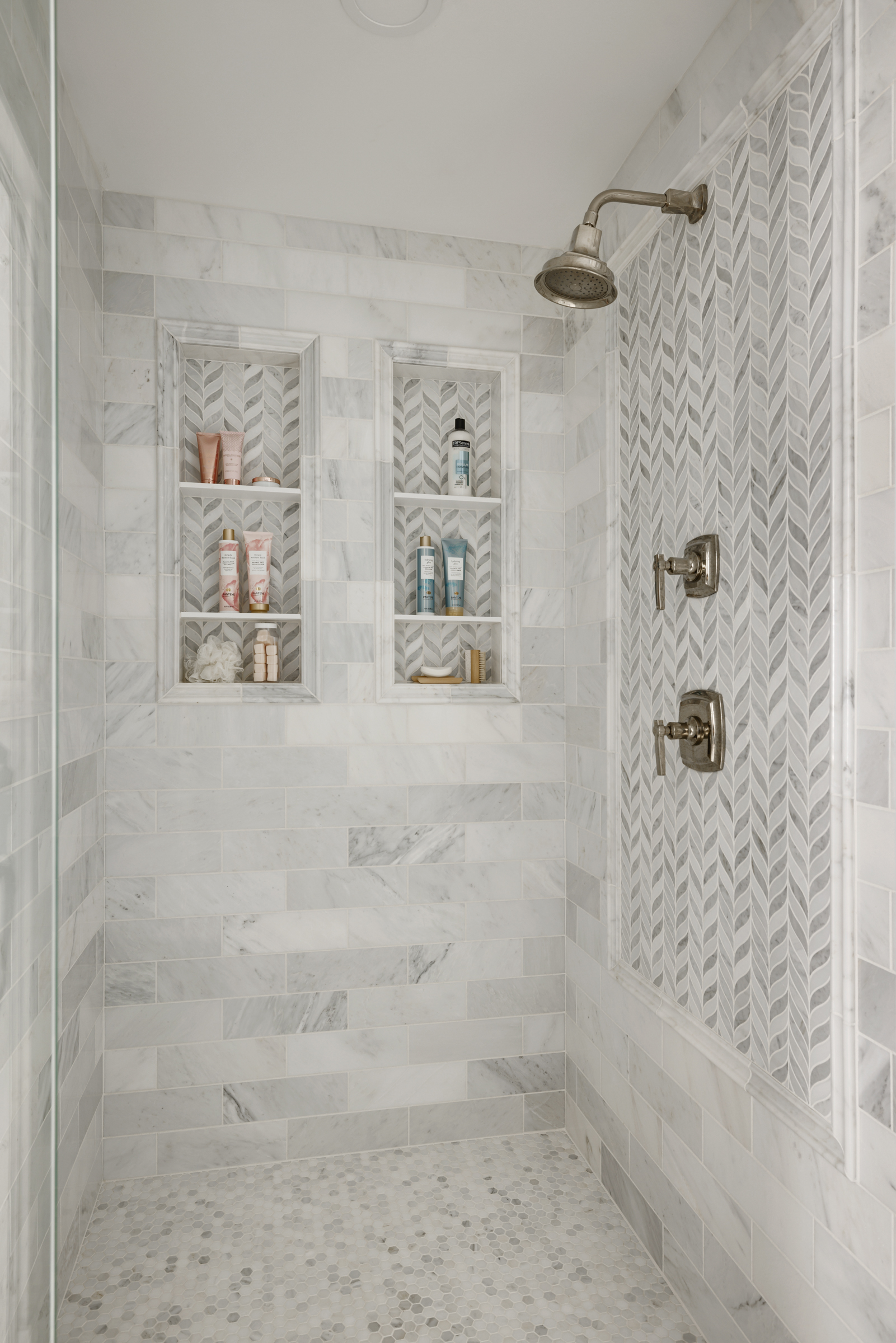 Luxury primary bathroom walk in shower with marble tile walls and built in storage